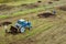 Blue tractor fertilizing a field, farmers spreading fertilizer with shovels, fertilizing fields