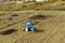 Blue tractor fertilizing a field, farmers spreading fertilizer with shovels, fertilizing fields