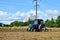 Blue tractor in a field of land plowing. Mechanization of tillage and crop planting.