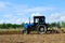 Blue tractor in a field of land plowing. Mechanization of tillage and crop planting. Loosening and preparing the land for sowing