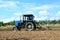 Blue tractor in a field of land plowing. Mechanization of tillage and crop planting. Loosening and preparing the land for sowing