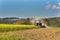 Blue tractor in a field of mustard in the Czech Republic. Dusty field and agricultural work. Autumn farm chores.