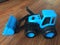 Blue tractor made of plastic on a brown wooden background. Toy blue bulldozer