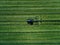 Blue tractor mowing green field, aerial view