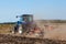 Blue tractor plows the field and removes the remains of previously mown corn. Part of the cultivator, steel, round discs in a row