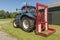 Blue tractor with a red bale slicer