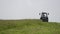 Blue tractor riding on grass margin at farm under gray sky