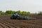 Blue tractor with seedbed cultivator works on a field on a spring morning