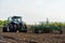 Blue tractor with seedbed cultivator works on a field on a spring morning