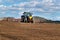 A blue tractor sows grain. Farm work on a farm in the Czech Republic. Tractor on a wheat field. Agricultural machinery