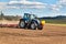 A blue tractor sows grain. Farm work on a farm in the Czech Republic. Tractor on a wheat field. Agricultural machinery