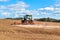 A blue tractor sows grain. Farm work on a farm in the Czech Republic. Tractor on a wheat field. Agricultural machinery