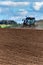 A blue tractor sows grain. Farm work on a farm in the Czech Republic. Tractor on a wheat field. Agricultural machinery