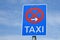 Blue traffic sigh with red crossed circle, arrow pointing to the right and word `Taxi` written on it