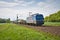 Blue train chugging down a set of tracks in a rural landscape.