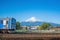 Blue train on railroad tracks with Mount Fuji