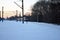 Blue train in snowy park, railroad along trees line, winter