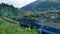 A blue train travels in the Carpathians past the village. Summer