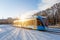 Blue tram rushes through the city in winter reflection of the sun\\\'s light effect