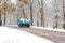 Blue truck with a load passing on a road with snow slush and snow fall