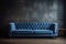 Blue tufted sofa against dark concrete wall with wooden paneling. Loft style interior design