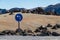 Blue turn left sign on a volcanic desert.