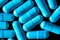 Blue turquoise capsule pills on a black background - drug, pharmaceutical