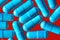 Blue turquoise capsule pills on a red background - drug, pharmaceutical