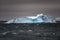 Blue and turquoise iceberg in dark Southern Ocean with dark and cloudy evening  sky in Antarctica