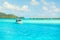 Blue turquoise lagoon and small boat on far bungalows background