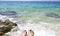 Blue and turquoise seacoast and women toes in the water on the beach