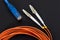 Blue twisted pair patch cord with fiber optics orange cable on dark background