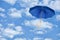 Blue umbrella flies in sky against of white clouds.Wind of chang