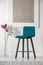 Blue velvet chair in elegant white interior with abstract silver painting on the wall