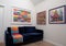 Blue velvet sofa with colourful wool blanket throw, in minimalist setting with white walls and colourful artwork.