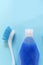 Blue vertical monochrome flay lay with copy space on top of brush and bottle with bubble liquid for cleaning.