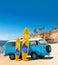 Blue Vintage, Retro, Old-fashioned mini bus van camper VW T2 with surfboard on beach, cliff, palm tree