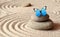 A blue vivid butterfly on a zen stone with circle patterns in the grain sand.