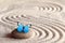 A blue vivid butterfly on a zen stone with circle patterns in the grain sand.