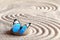 A blue vivid butterfly on a zen stone with circle patterns in the grain sand
