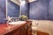 Blue walls bathroom interior with mahogany vanity cabinet.