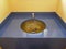 Blue wash basin with modern round sink made of golden brown glass.