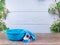 Blue washing up bowl, brush, blue rubber gloves, cleaning set on spring background, pastel wooden planks and spring