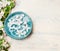 Blue water bowl with pretty spring blossom on light shabby chic background, top view