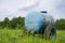 Blue water cistern drink for farm animal in meadow