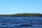 Blue water clear sky sunny day on finnish lake water waves close up. Beauty of nature skyline and forest with deep colored water.