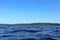 Blue water clear sky sunny day on finnish lake water waves close up. Beauty of nature skyline and forest with deep colored water.