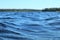 Blue water clear sky sunny day on finnish lake water waves close up. Beauty of nature skyline and forest with deep colored water.