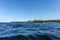 Blue water clear sky sunny day on finnish lake water waves close up. Beauty of nature skyline and forest with deep colored water.