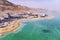 Blue water in the dead sea in the foreground on the background of the resort town of Ein Bokek in the middle of the desert in